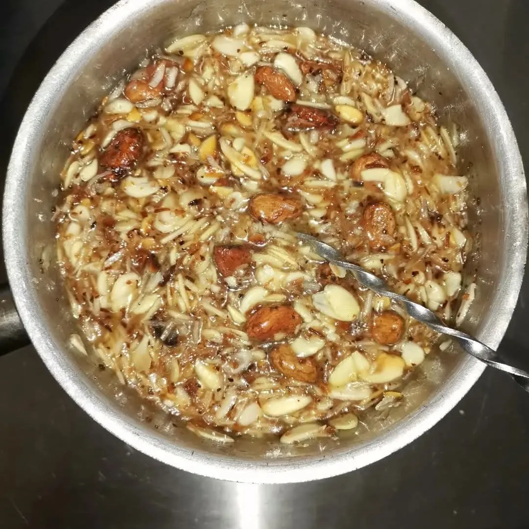 Recipiente metálico con ingredientes laminados en un líquido y una cuchara.
