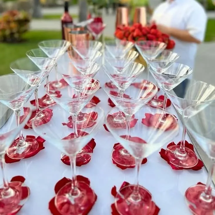 Filas de copas de cóctel con una preparación roja en el fondo, listas para el servicio.